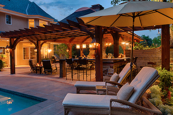 Illuminated poolside pergola with outdoor kitchen for dining and entertaining