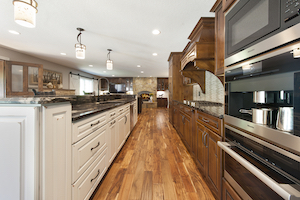 Rustic wide plank wood flooring unites contrasting cabinetry