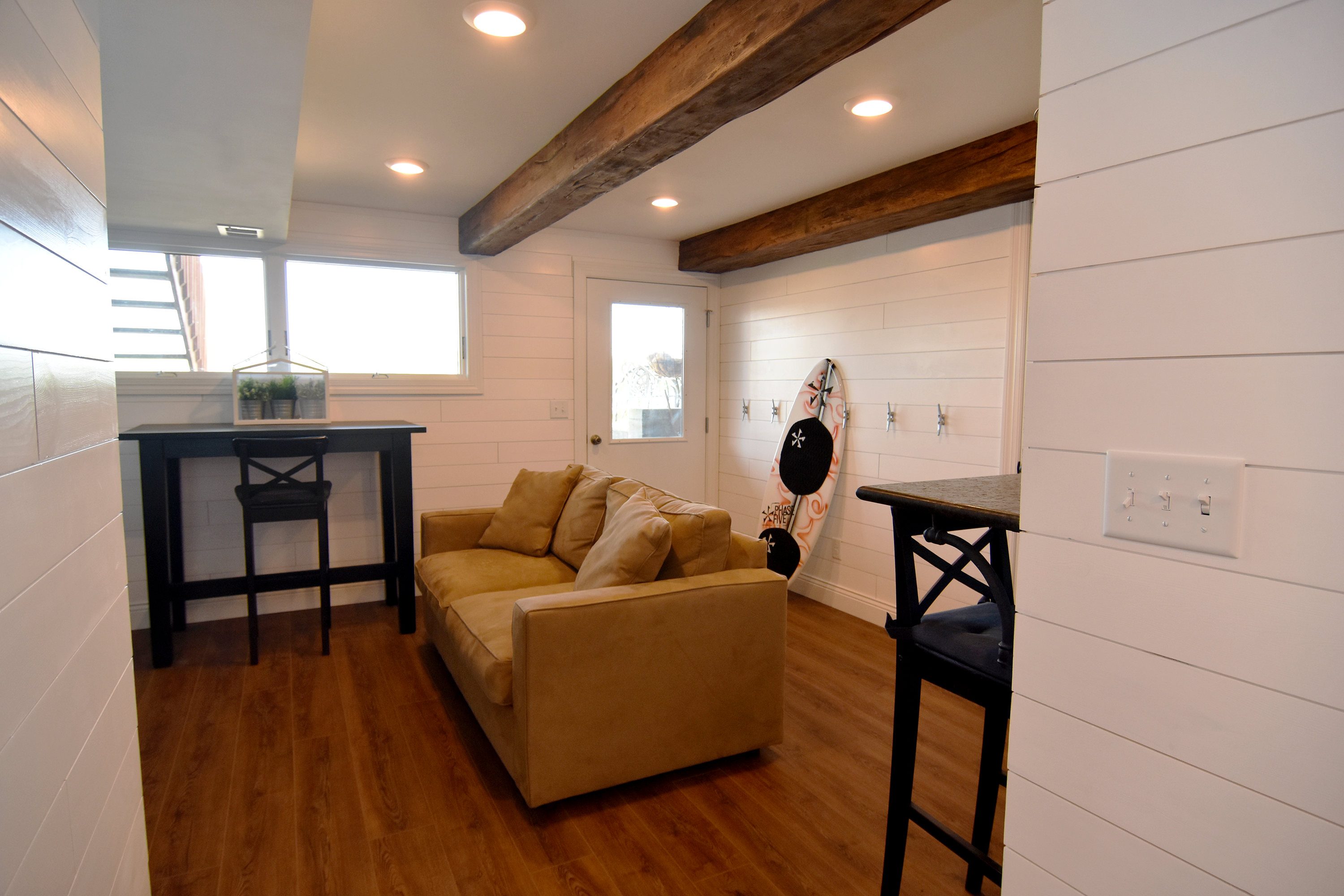 Cozy Basement - Hangout Space - View of couch and hightop tables on hardwood floors